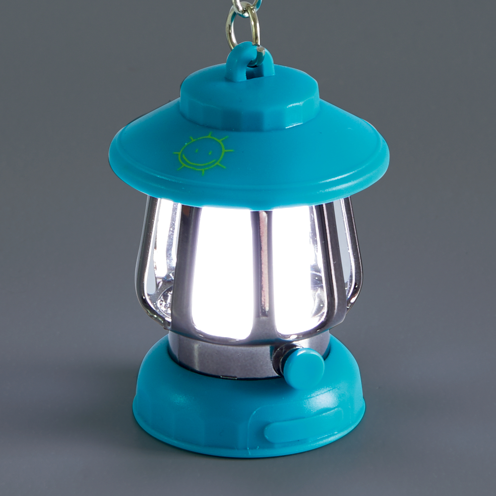 Kleine türkise Laterne mit silbernem Mittelteil und eingeschaltetem Licht, am Schirm mit kleinem Sonnenmotiv.