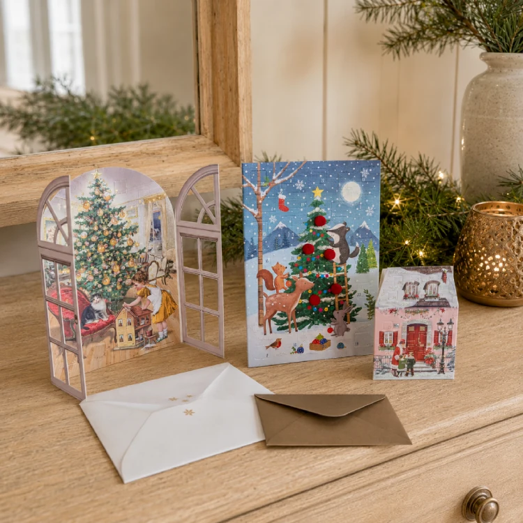 Mehere weihnachtliche Grußkarten mit Umschlägen auf einer dekorierten Kommode.