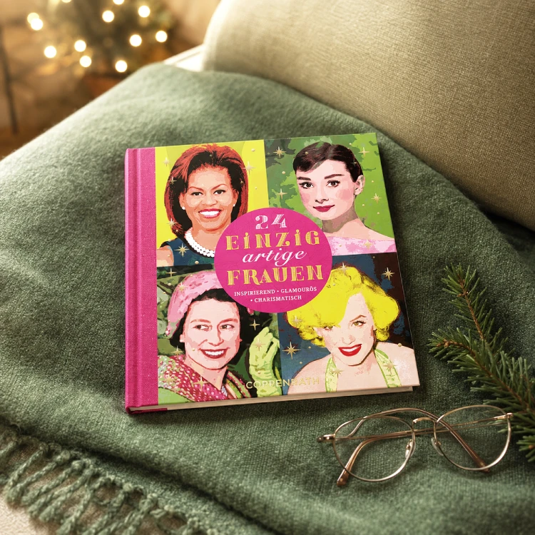 Ein Buch mit 4 Frauen auf dem Cover liegt auf einer Wolldecke neben einer Brille.